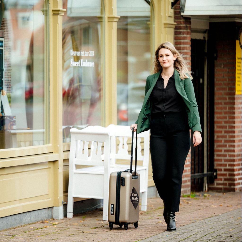 Vrouw die voor een winkel langsloopt met een koffer.