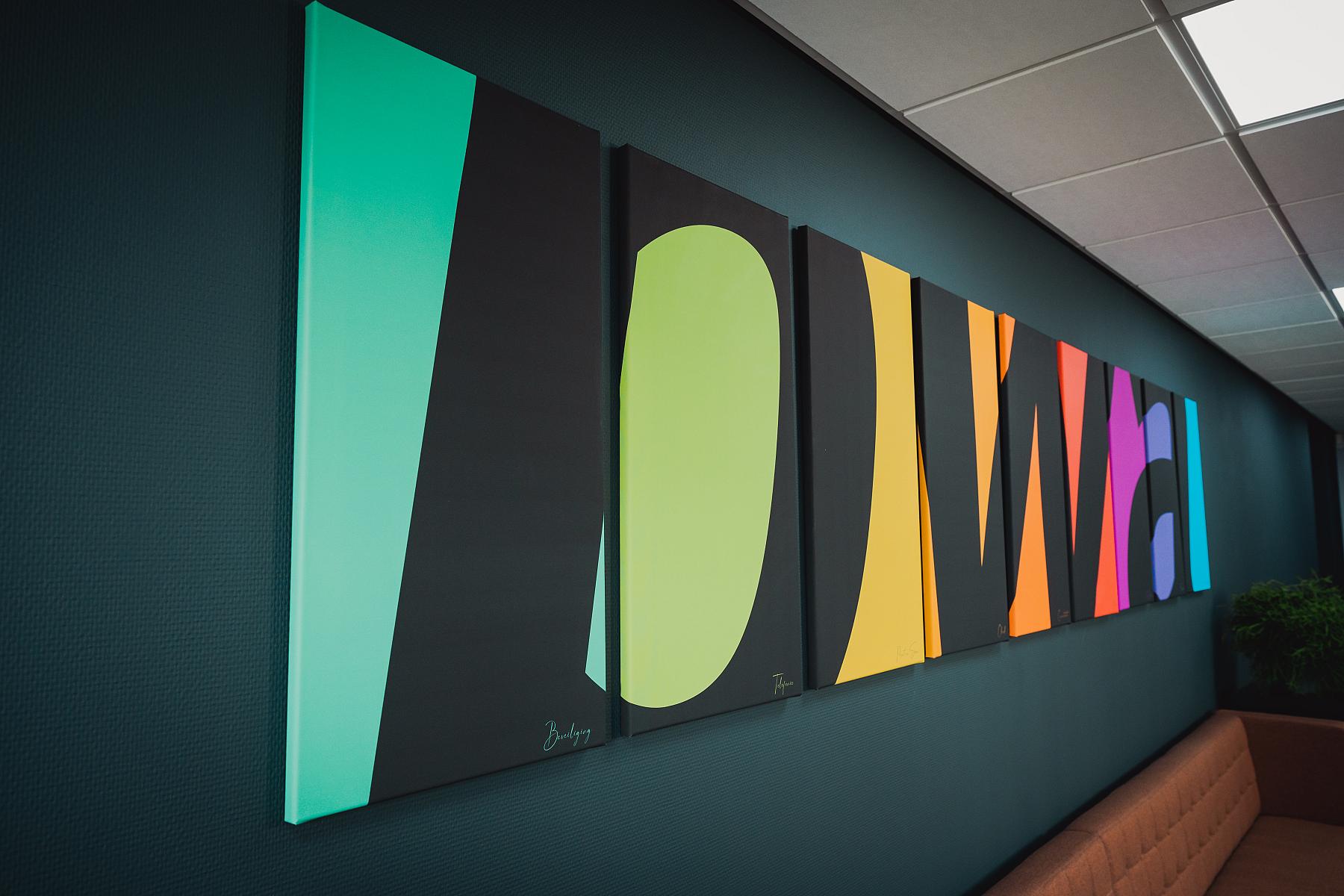 Logo van PWA in bedrijfskleuren hangend aan de muur.